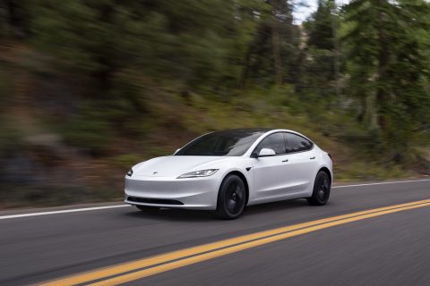 Tesla Model 3 Standard blanche, vue de trois quarts avant, en conduite sur route foresti&egrave;re