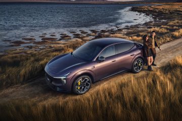 Xpeng L03 mauve gar&eacute; sur un chemin de terre au bord d'un lac, au coucher du soleil, avec un couple appuy&eacute; contre la carrosserie.