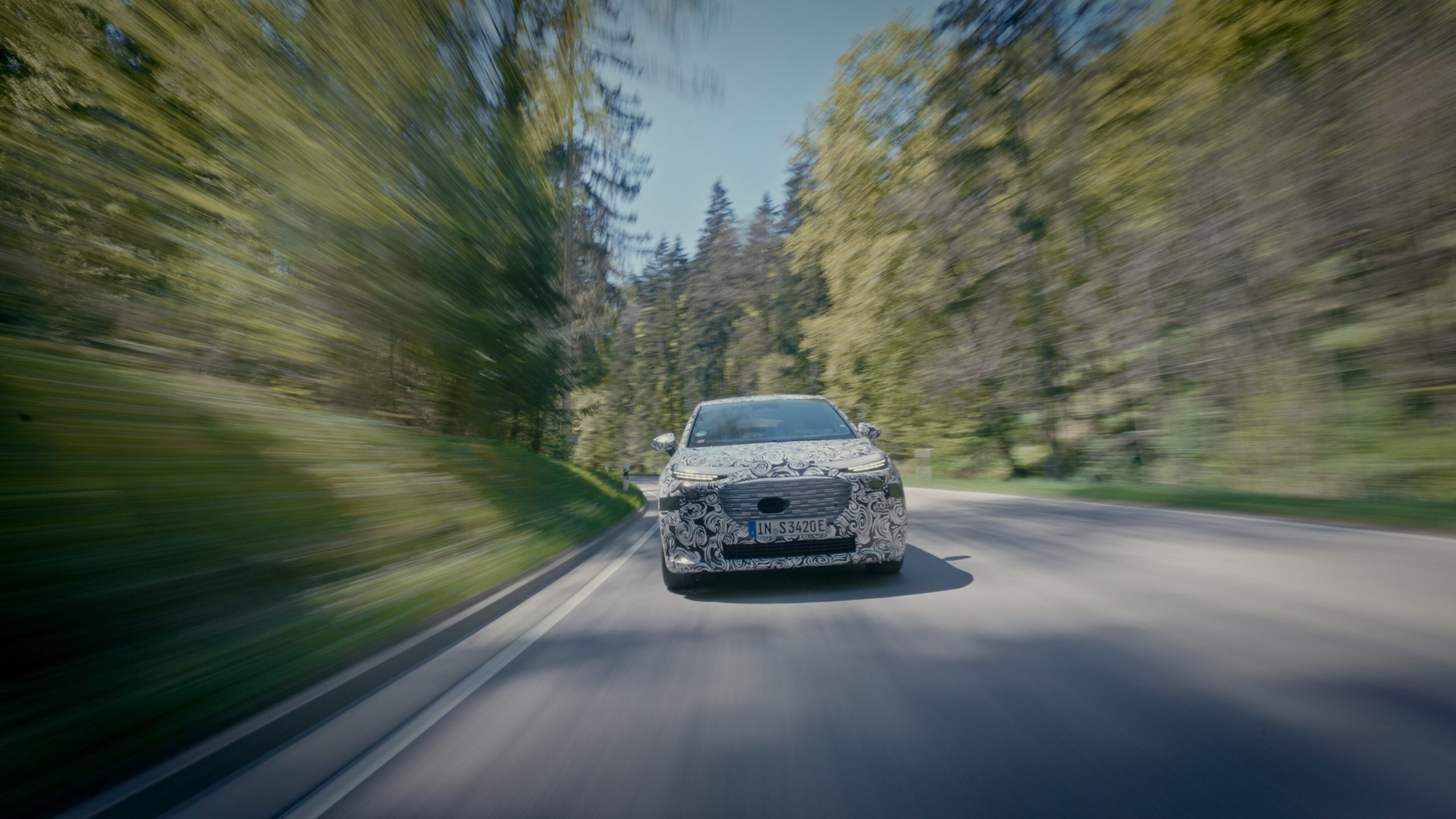 Prototype camoufl&eacute; de l'Audi A2 e-tron roulant sur une route de for&ecirc;t.