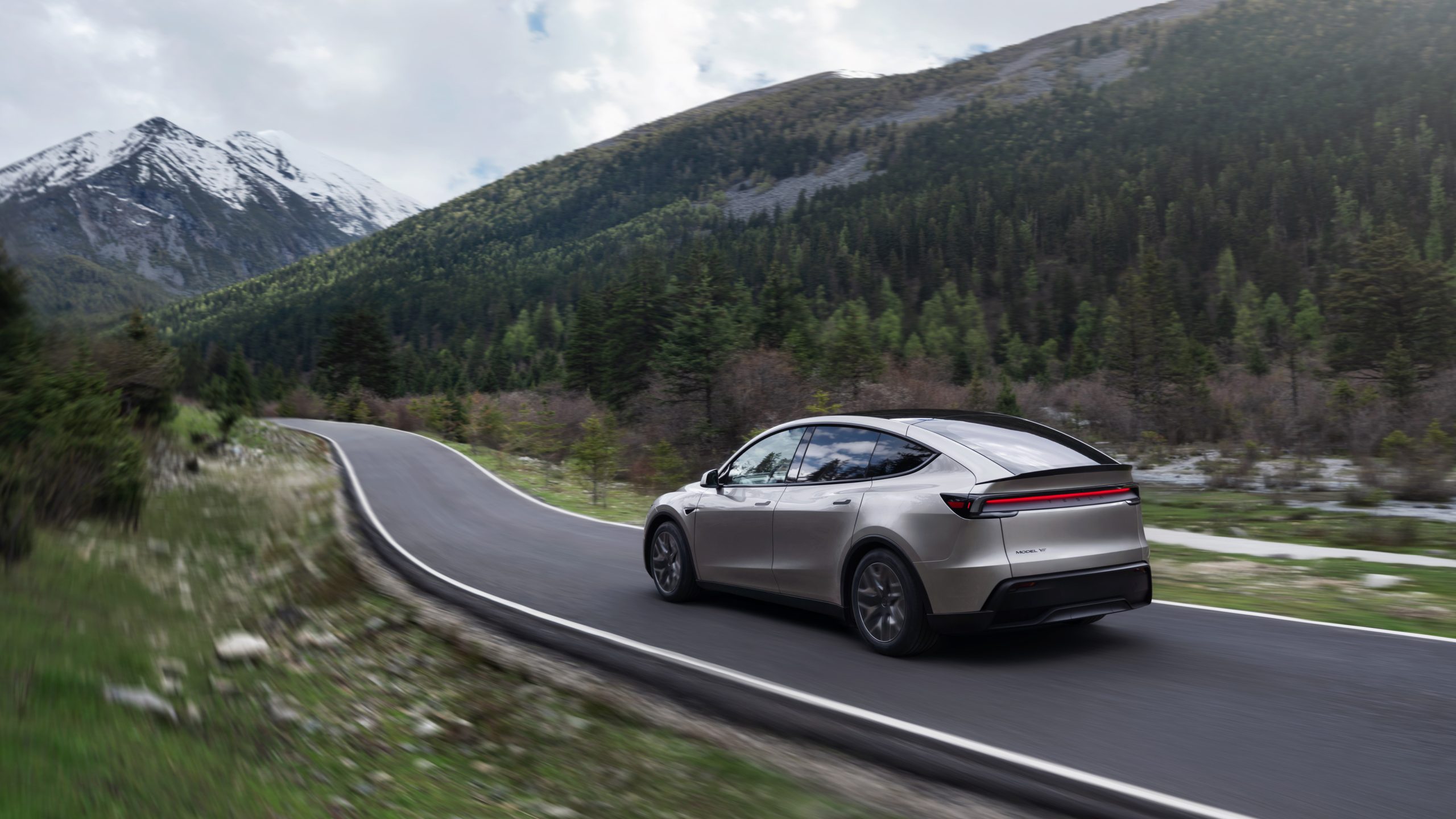 Tesla Model Y L gris roulant sur une route de montagne.