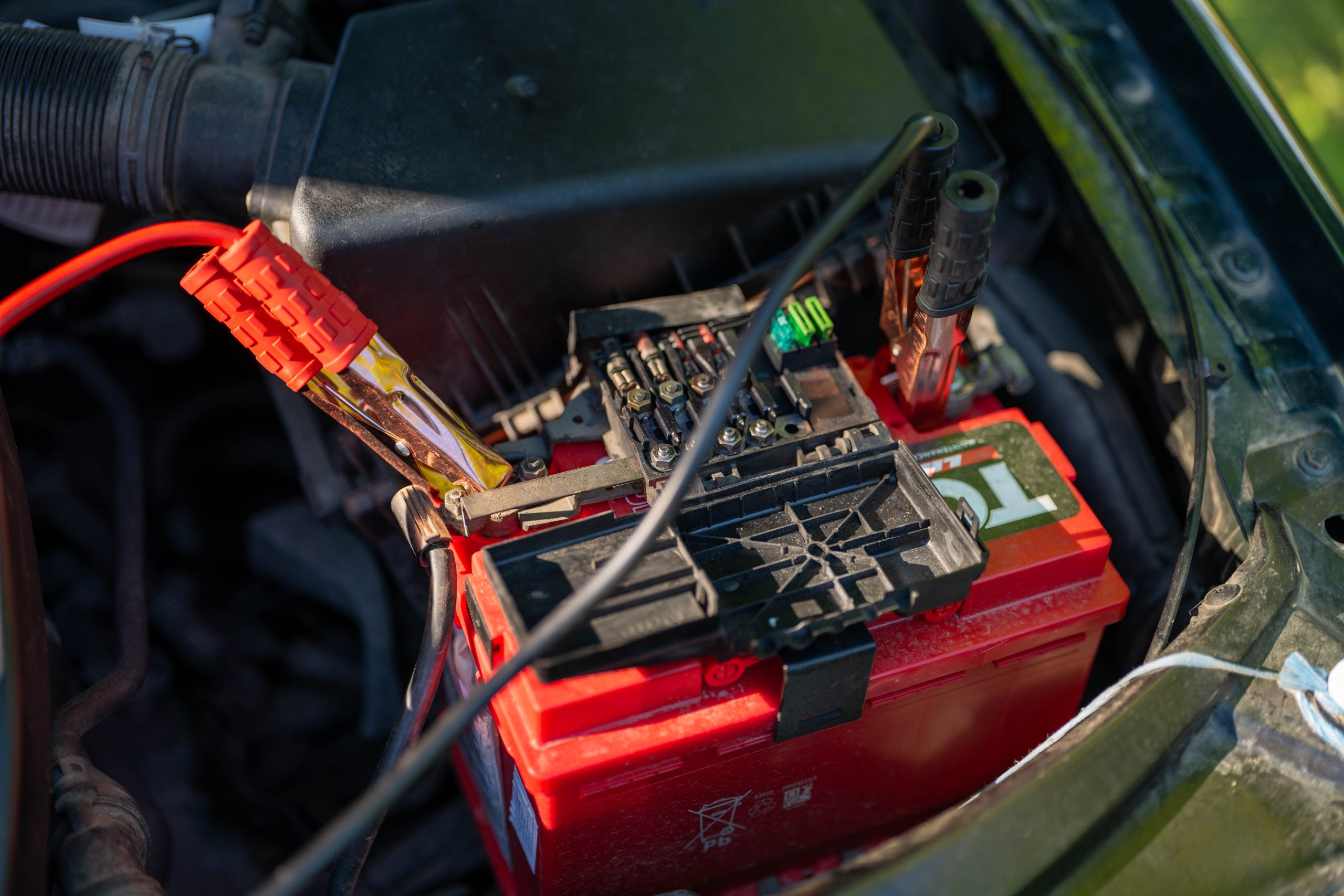 Batterie de voiture avec des c&acirc;bles de d&eacute;marrage rouges branch&eacute;s sur les bornes